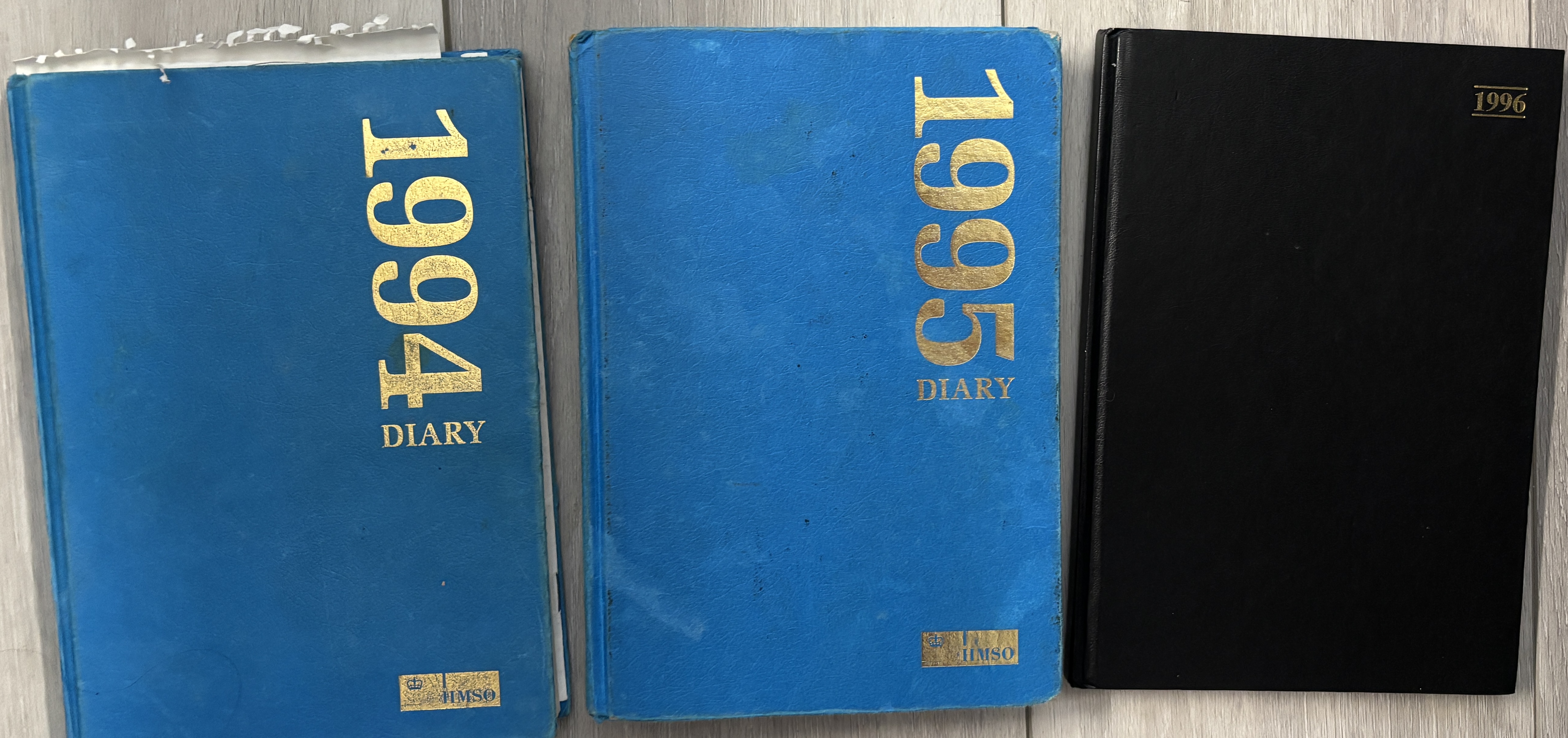 Three training diaries from 1994, 1995 and 1996 lying side by side — two blue HMSO diaries and one black