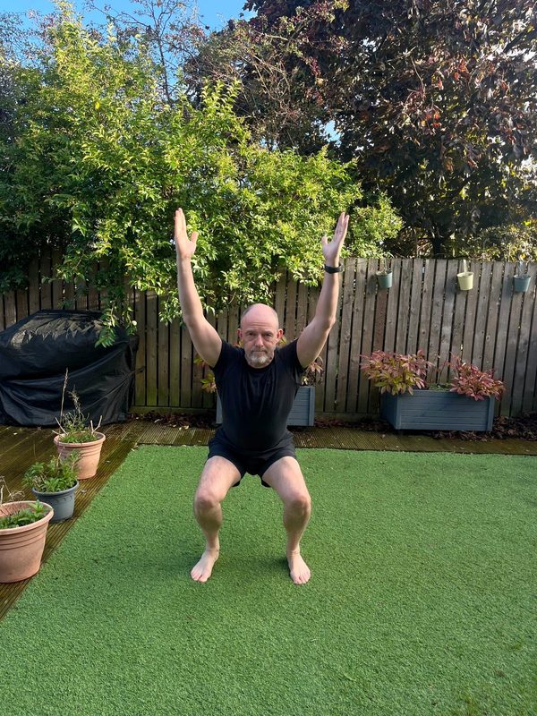 Stephen in a deep squat with arms overhead, front view, torso upright