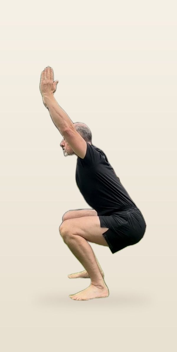 Stephen in a deep squat with arms overhead, side view: arms in line with the spine, feet flat
